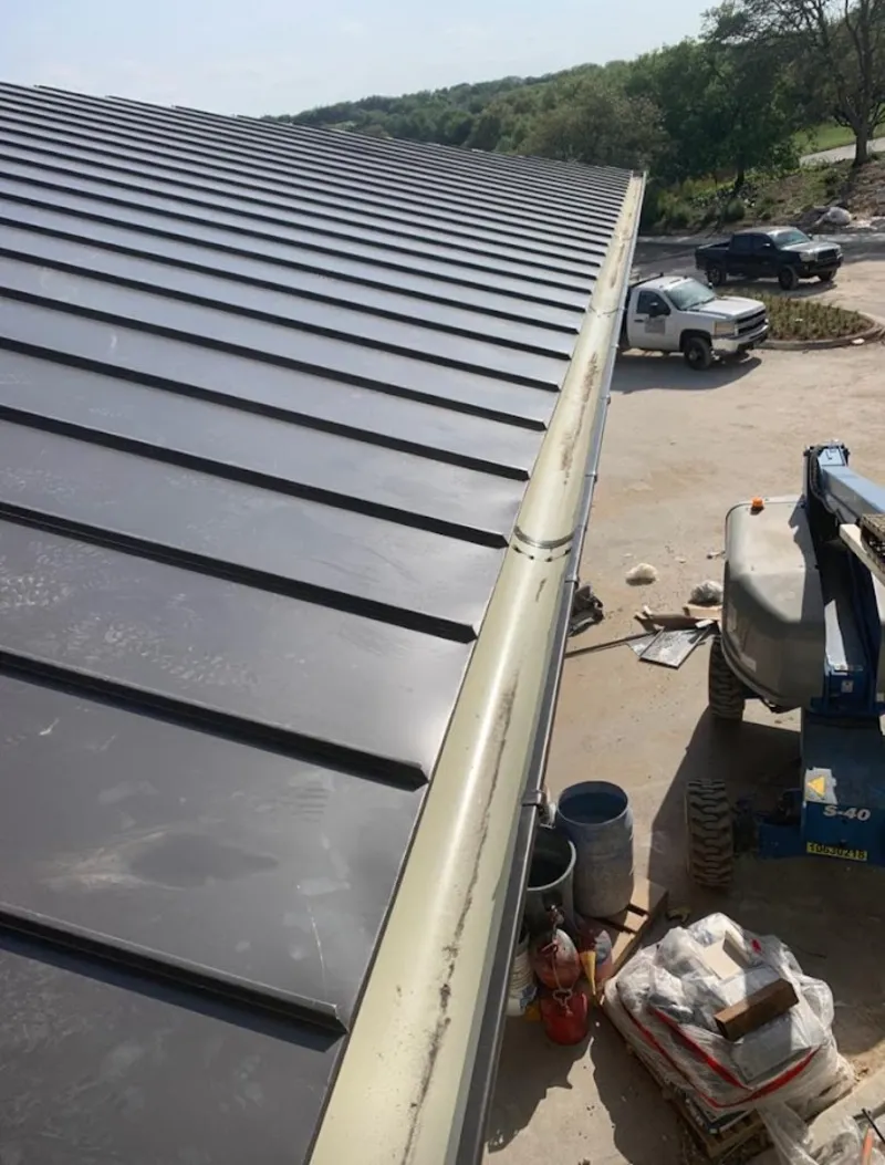 Standing seam panel and gutter detail on a metal roofing jobsite in Helotes